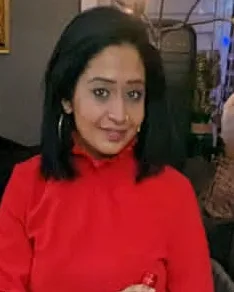 Professional woman in red dress holding wine bottle at evening event