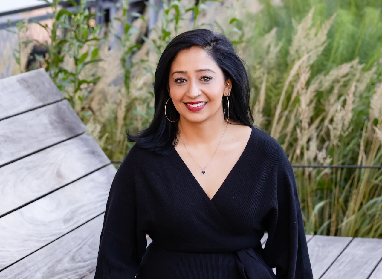 a girl sitting on a bench smiling in a black dress