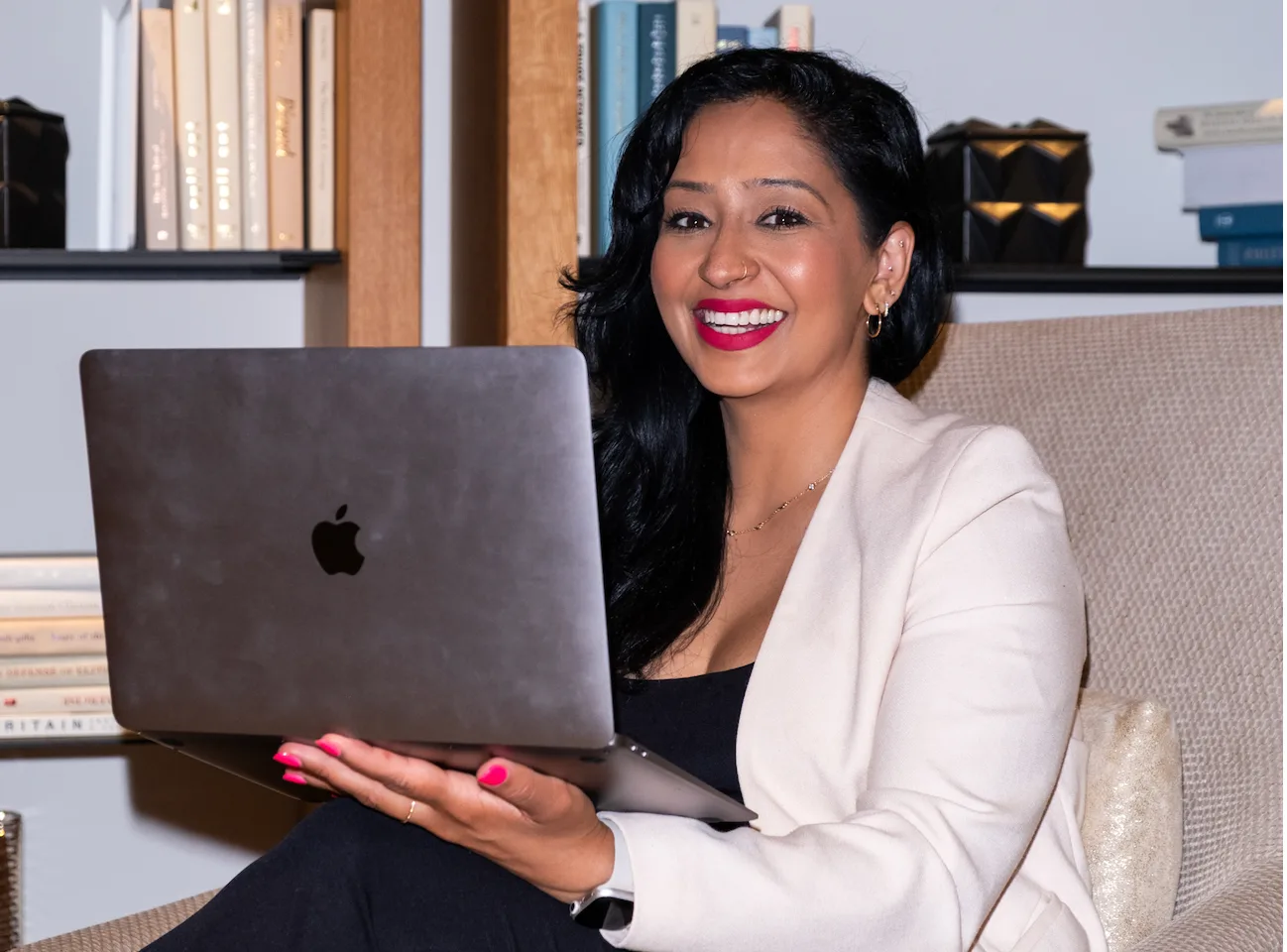 a professional woman sitting crossed legged with her laptop smiling