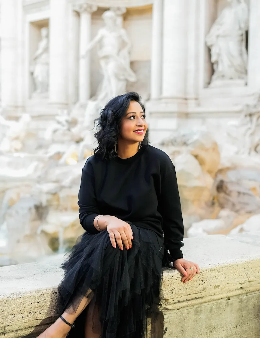 a women sitting in front of the Trevi Fountain in Rome
